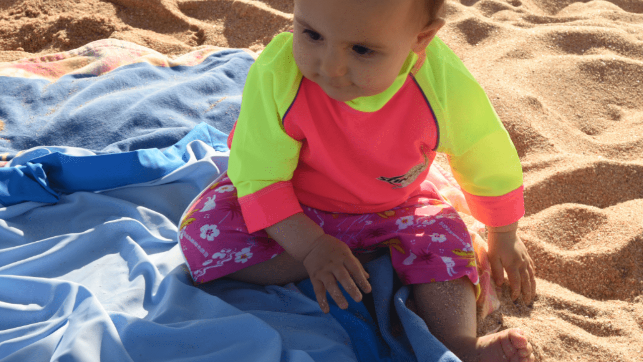 Baby wearing upf50 rash shirt on the beach