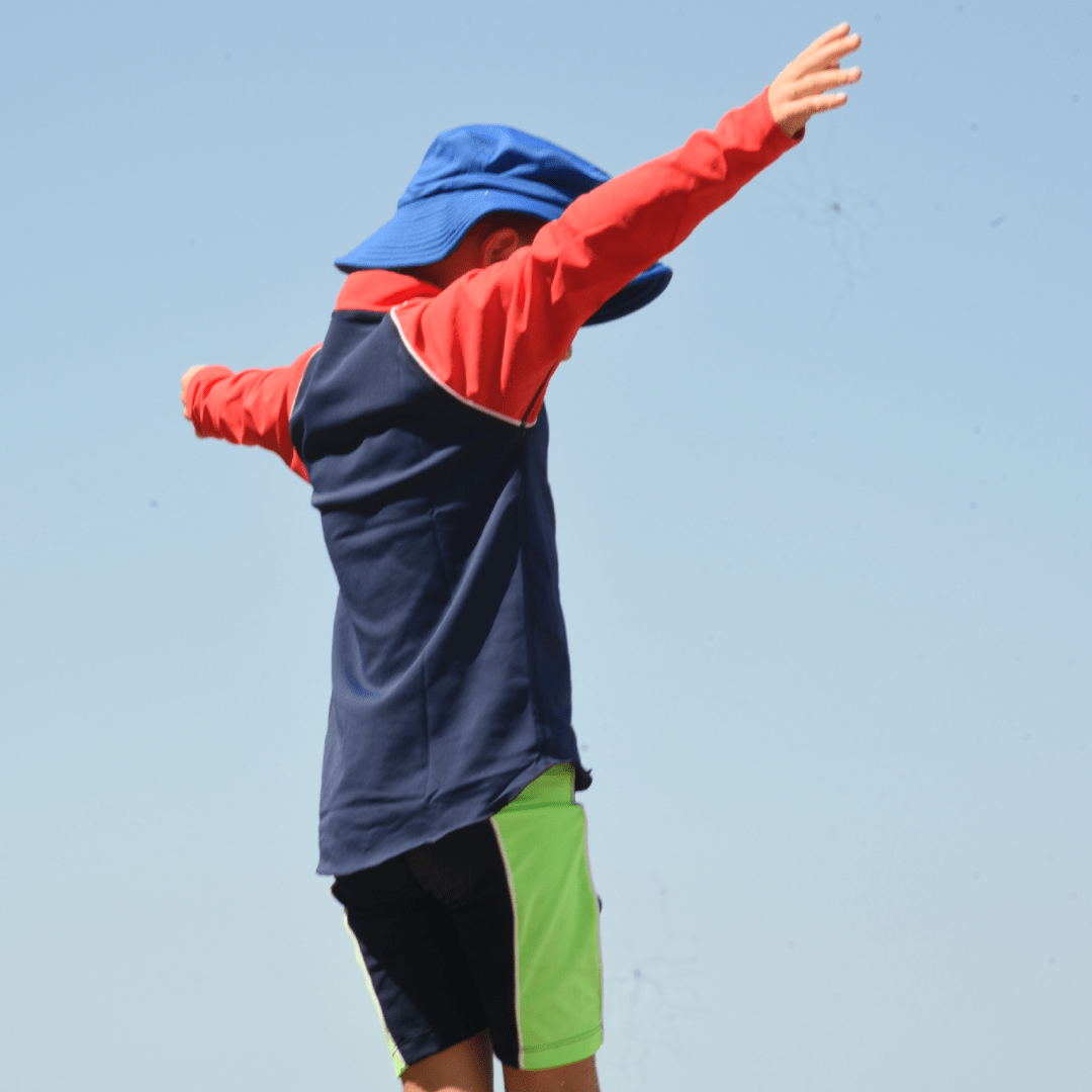 Child wearing a colourful UPF 50+ rash shirt with a blue sky background
