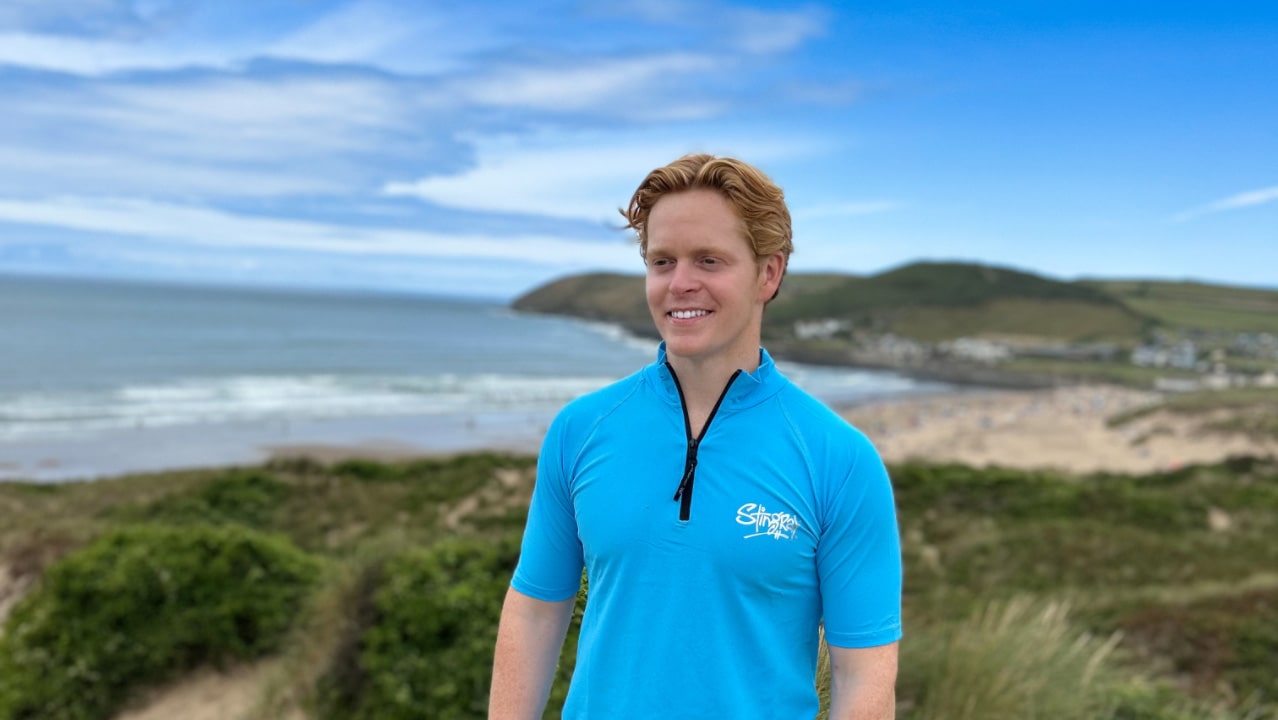 Man wearing a blue upf50 rash shirt on a beach