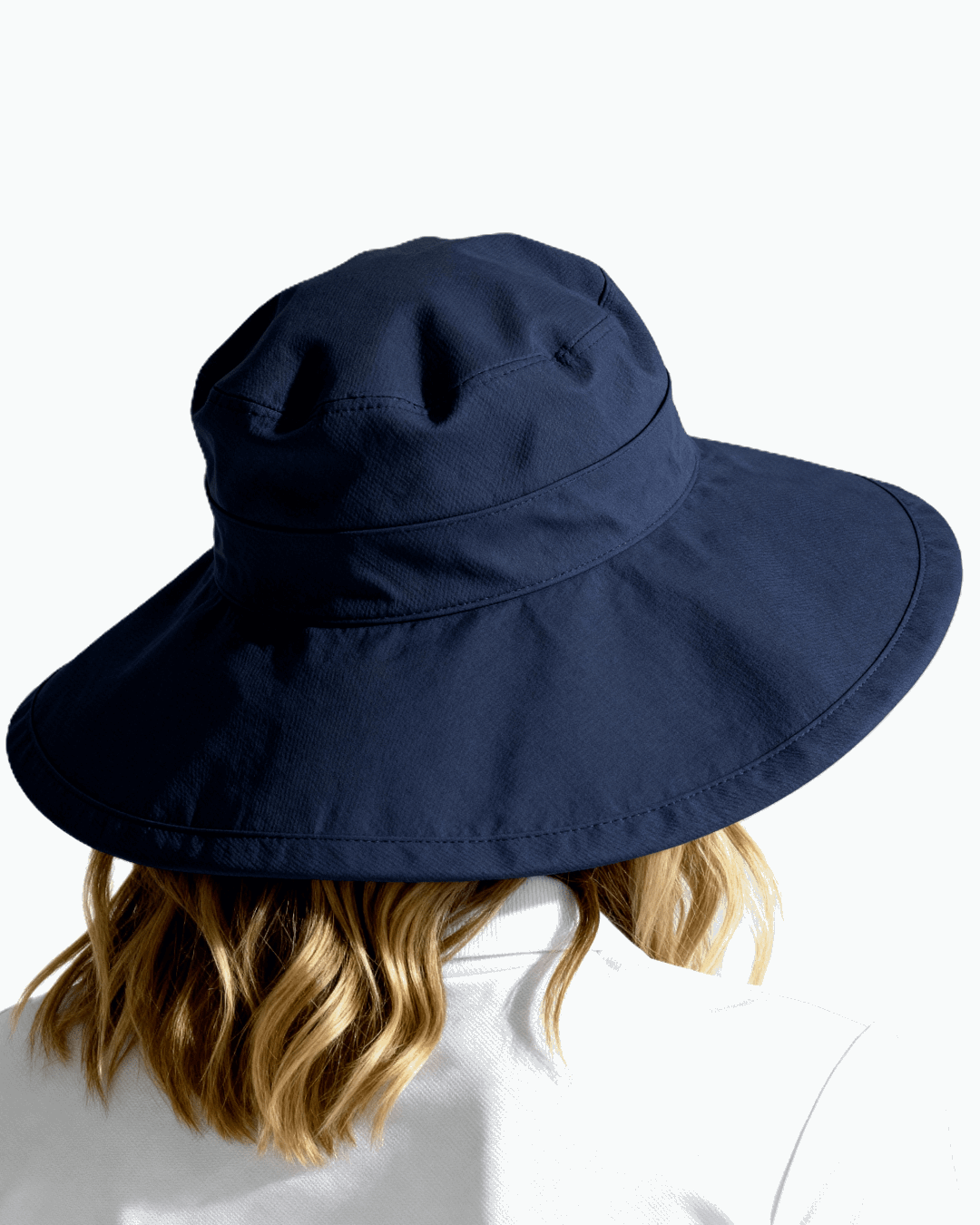Behind angle of a woman wearing navy blue Stingray Sun Hat with 4-inch wide brim and UPF 50+ sun protection.