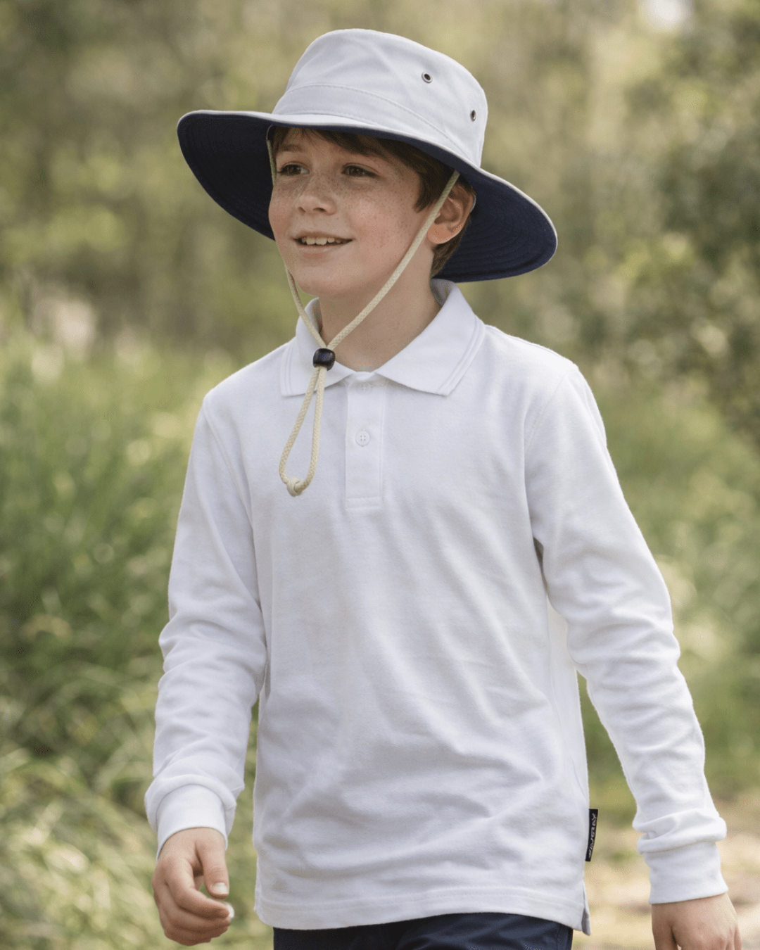 Child wearing a white long-sleeve shirt and wide-brimmed UPF 50+ cricket hat outdoors