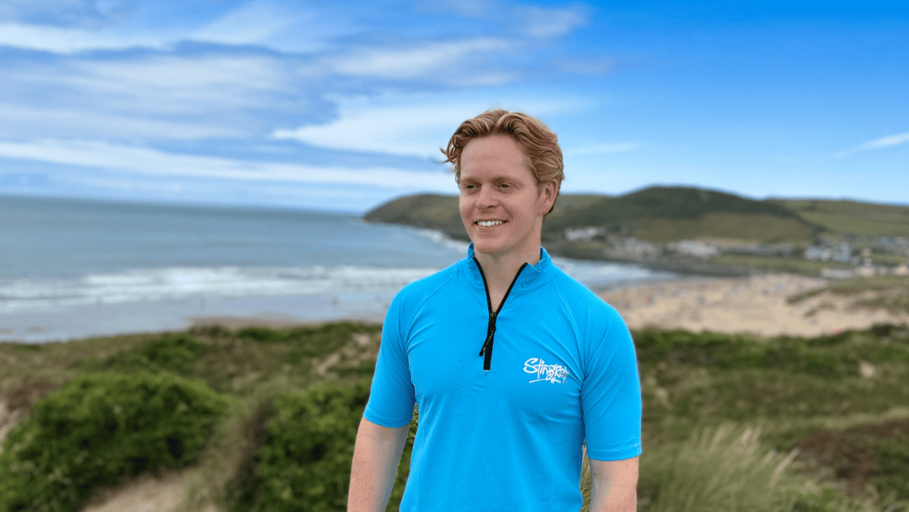 Man wearing a blue upf50 rash shirt on a beach