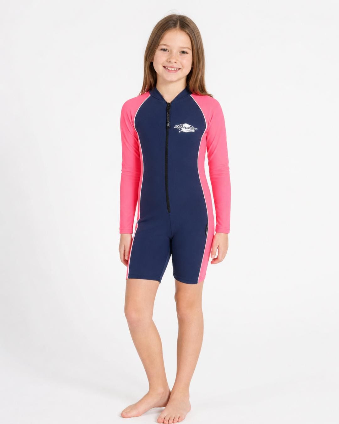 10 year old girl wearing a long sleeve UV swimsuit in navy and pink standing in a white studio