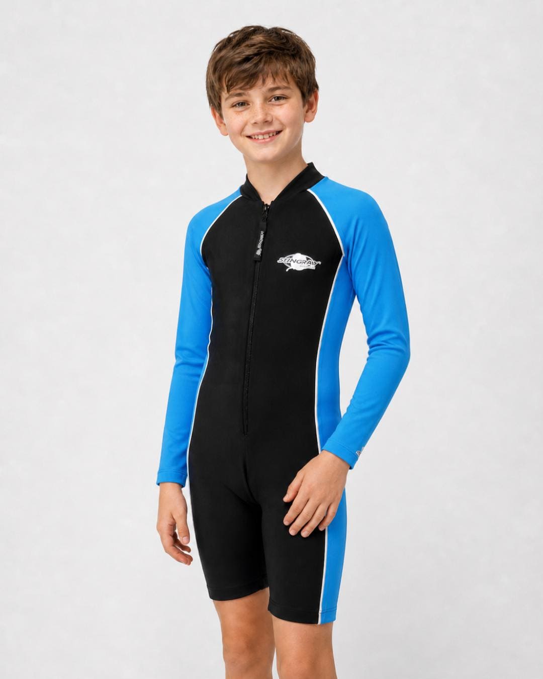 14 year old boy wearing a long sleeve UV swimsuit in black and azure standing in a white studio