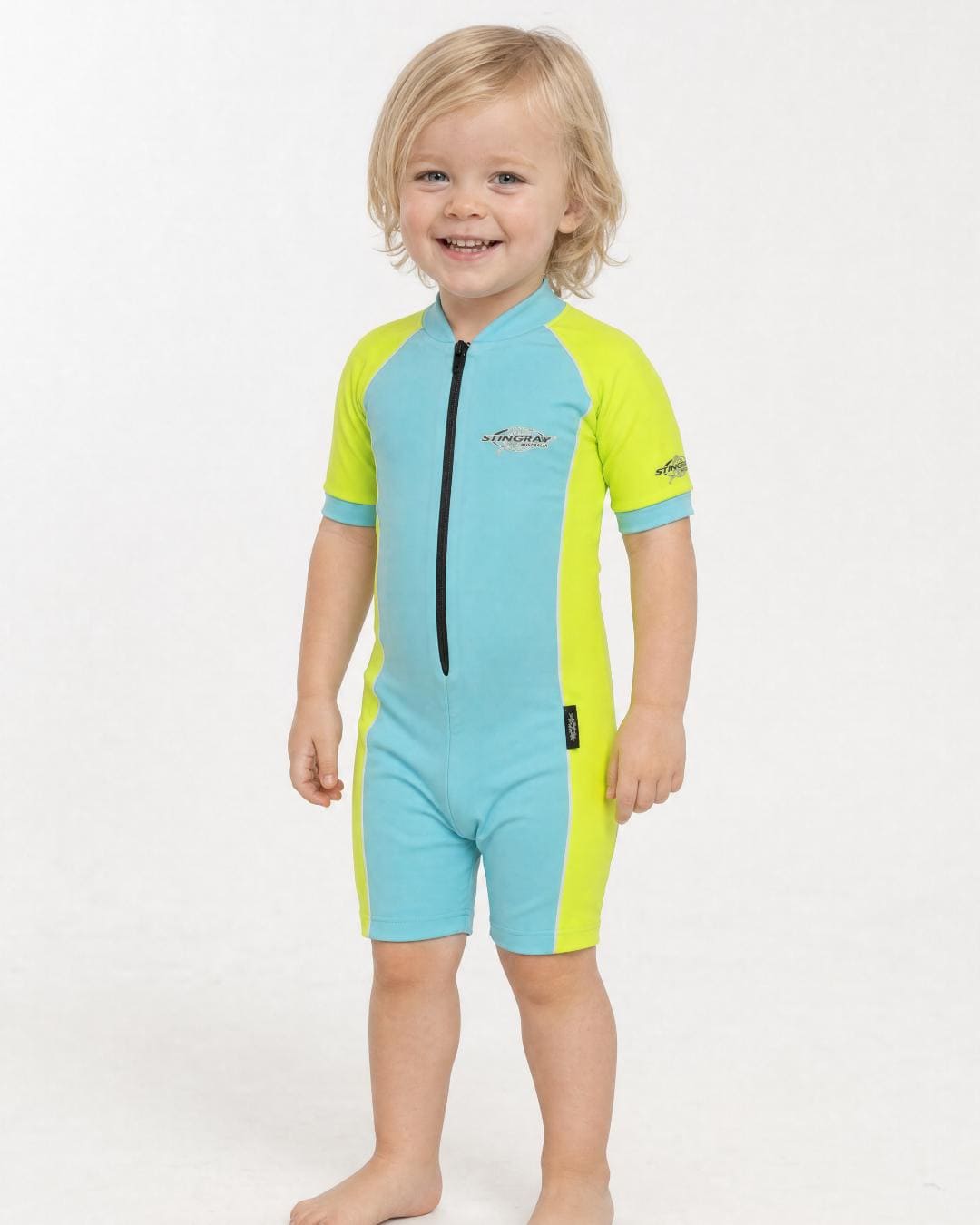 2 year old toddler wearing short sleeve UV sunsuit UPF 50+ in aqua and yellow in a white studio 