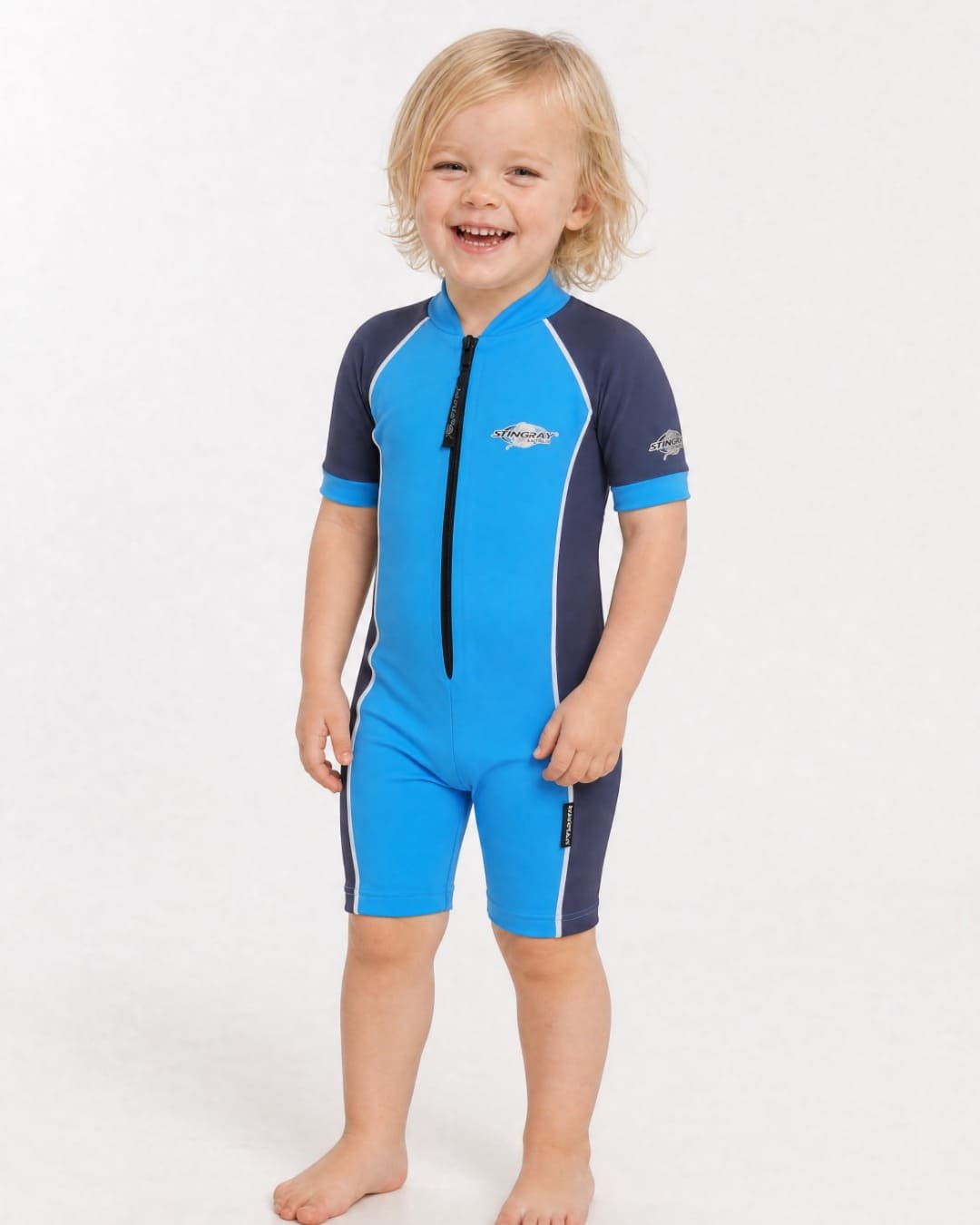 2 year old toddler wearing short sleeve UV sunsuit UPF 50+ in azure and navy in a white studio 