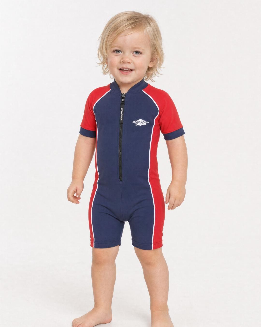 2 year old toddler wearing short sleeve UV sunsuit UPF 50+ in navy and red in a white studio 