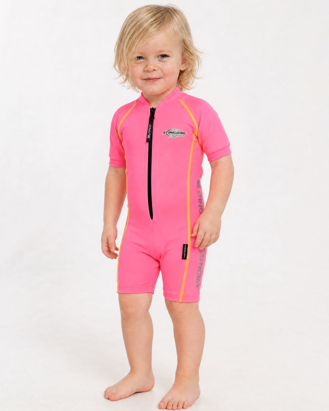 2 year old toddler wearing short sleeve UV sunsuit UPF 50+ in pink in a white studio 