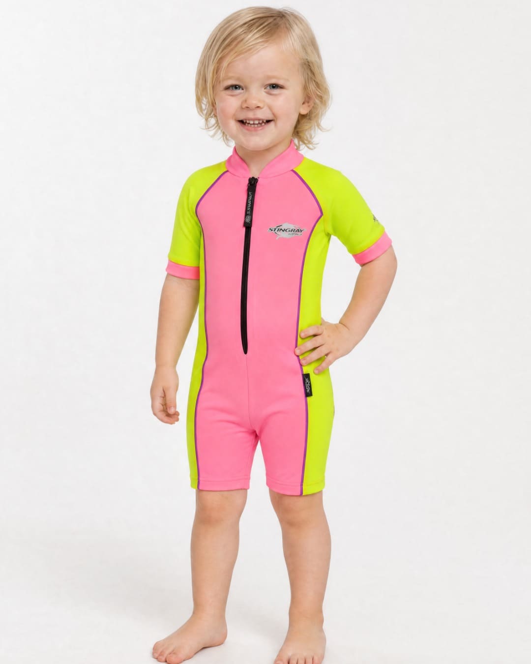 2 year old toddler wearing short sleeve UV sunsuit UPF 50+ in pink and yellow in a white studio 