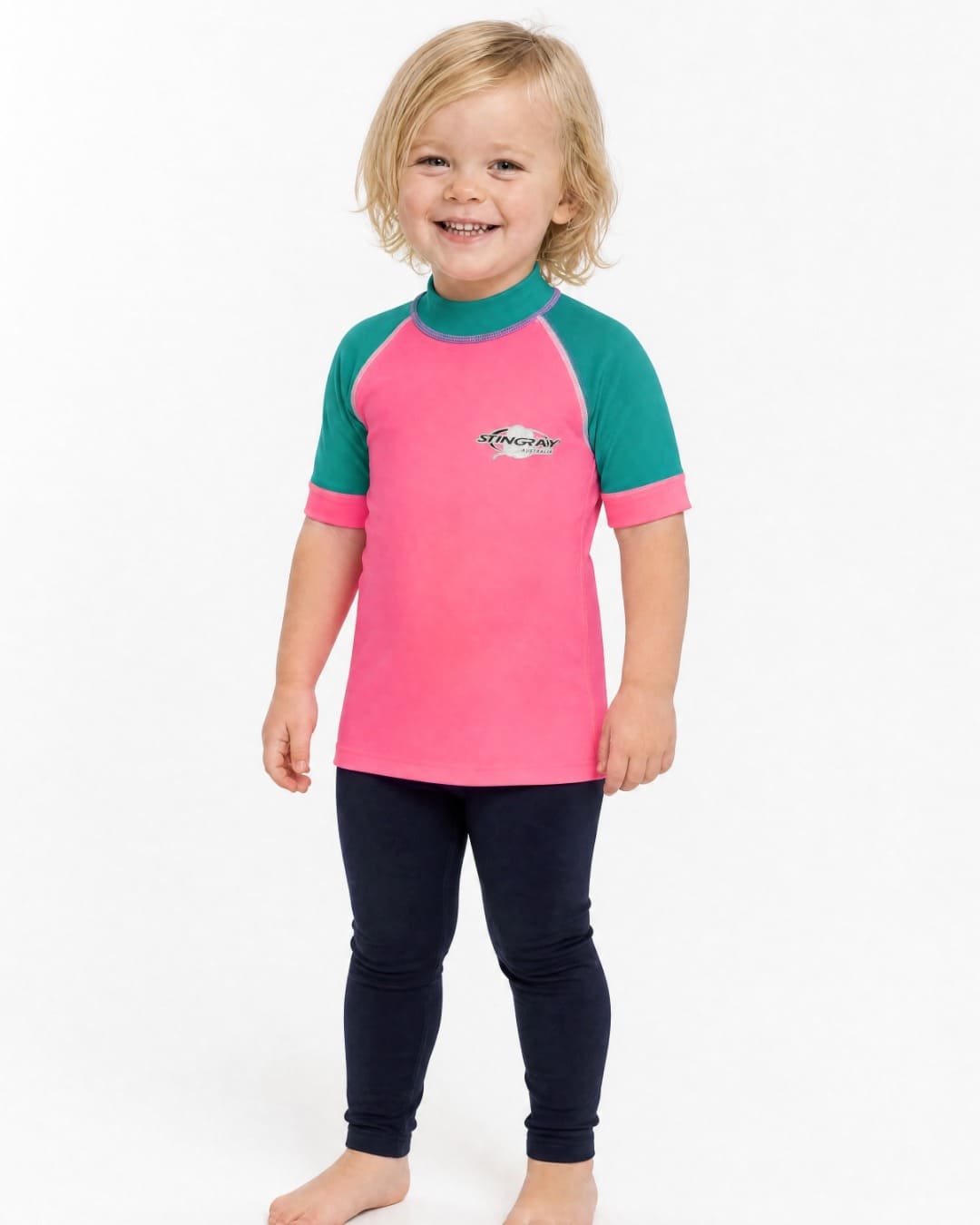 2 year old wearing a short sleeve UV swim shirt UPF 50+ in pink and teal in a white studio