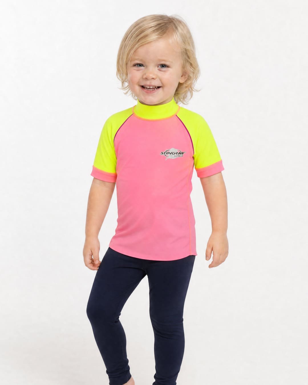 2 year old wearing a short sleeve UV swim shirt UPF 50+ in pink and yellow in a white studio