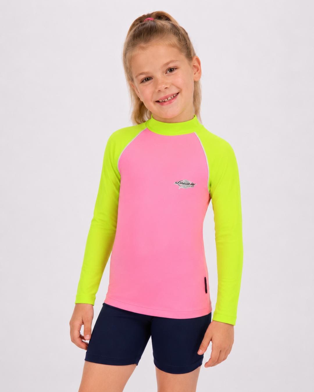 6 year old girl wearing a pink and yellow long-sleeve UV rash vest on a white background