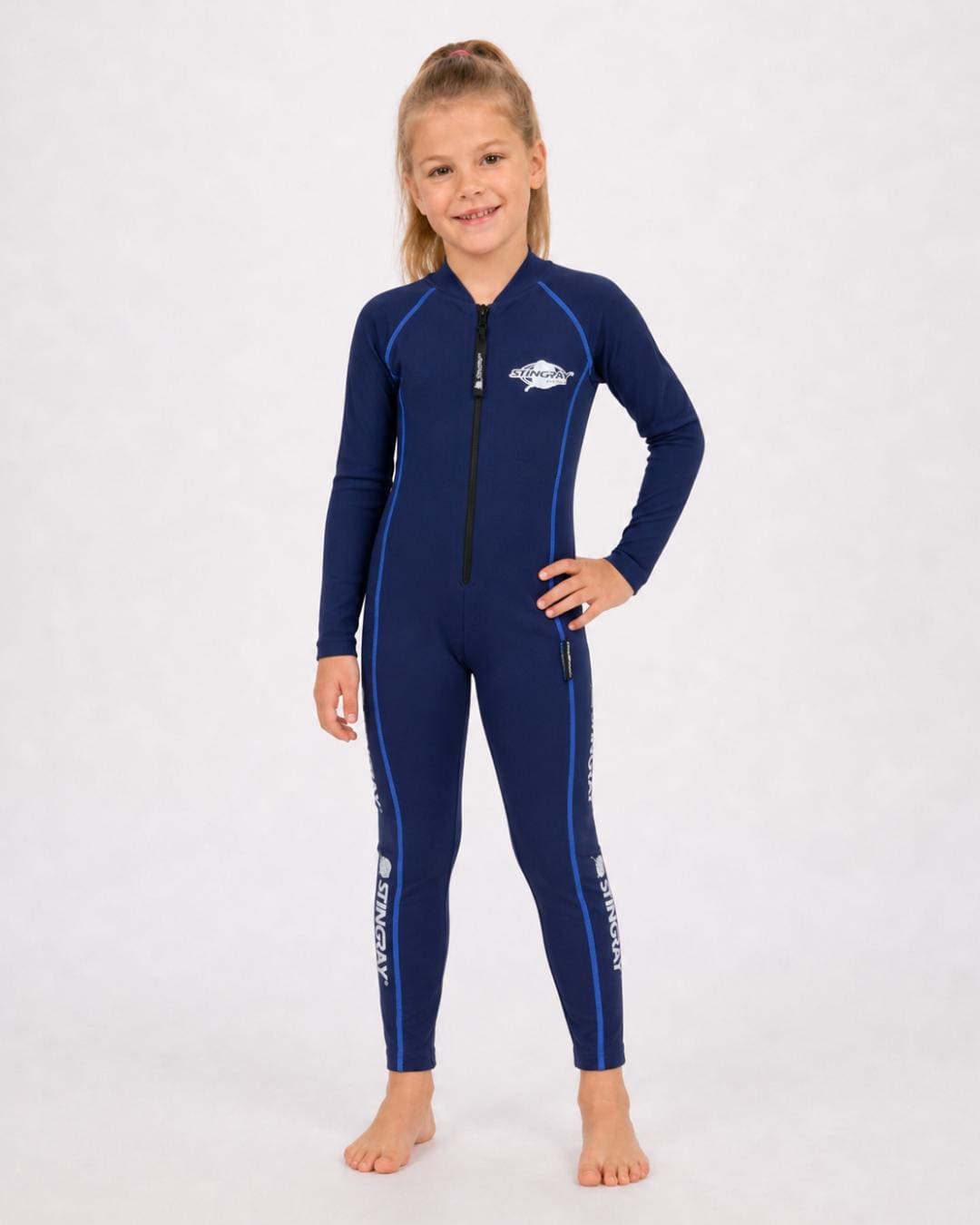 6 year old girl wearing a navy, with blue stitching, full-body UV swimsuit on a white background