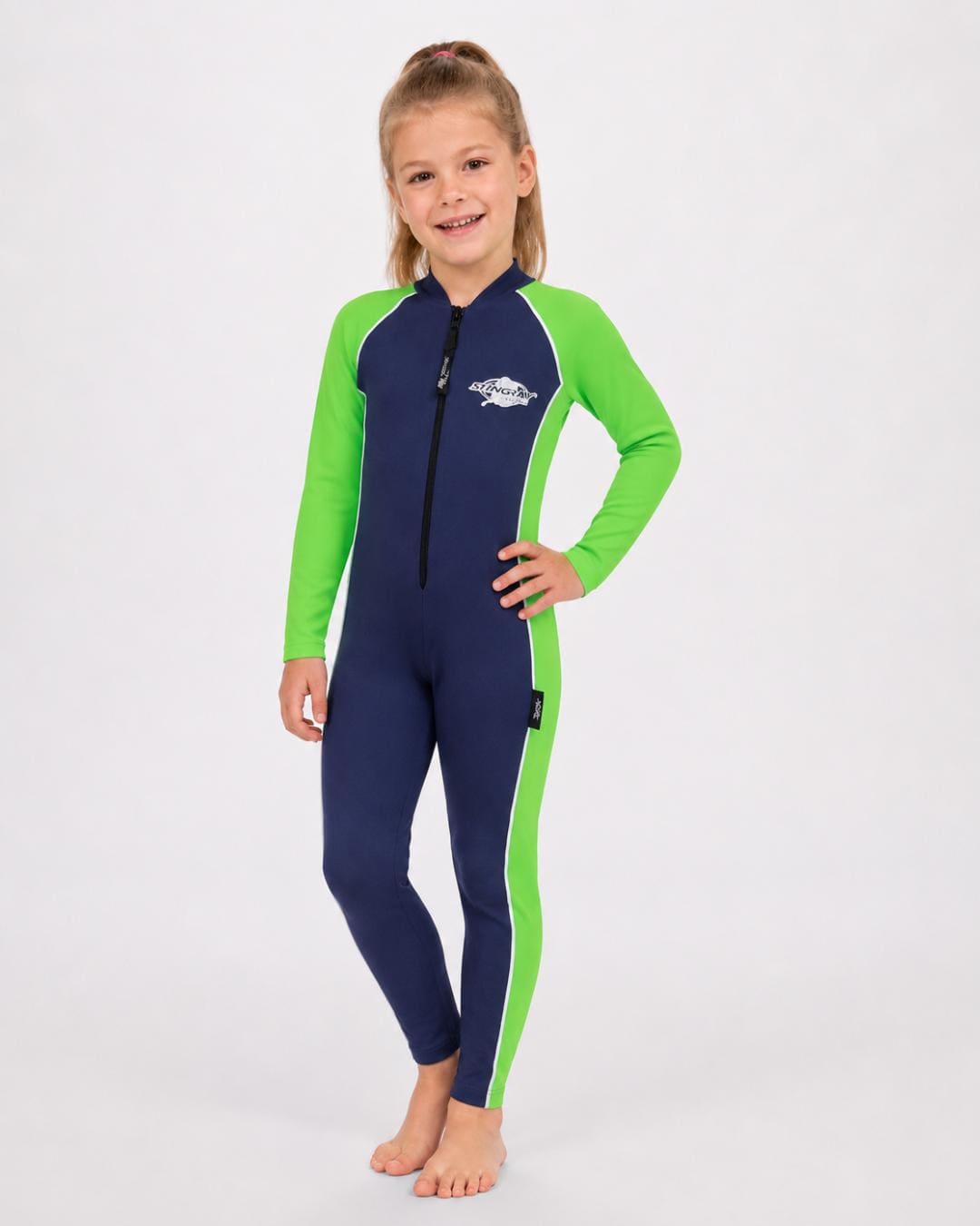 6 year old girl wearing a navy and green full-body UV swimsuit on a white background