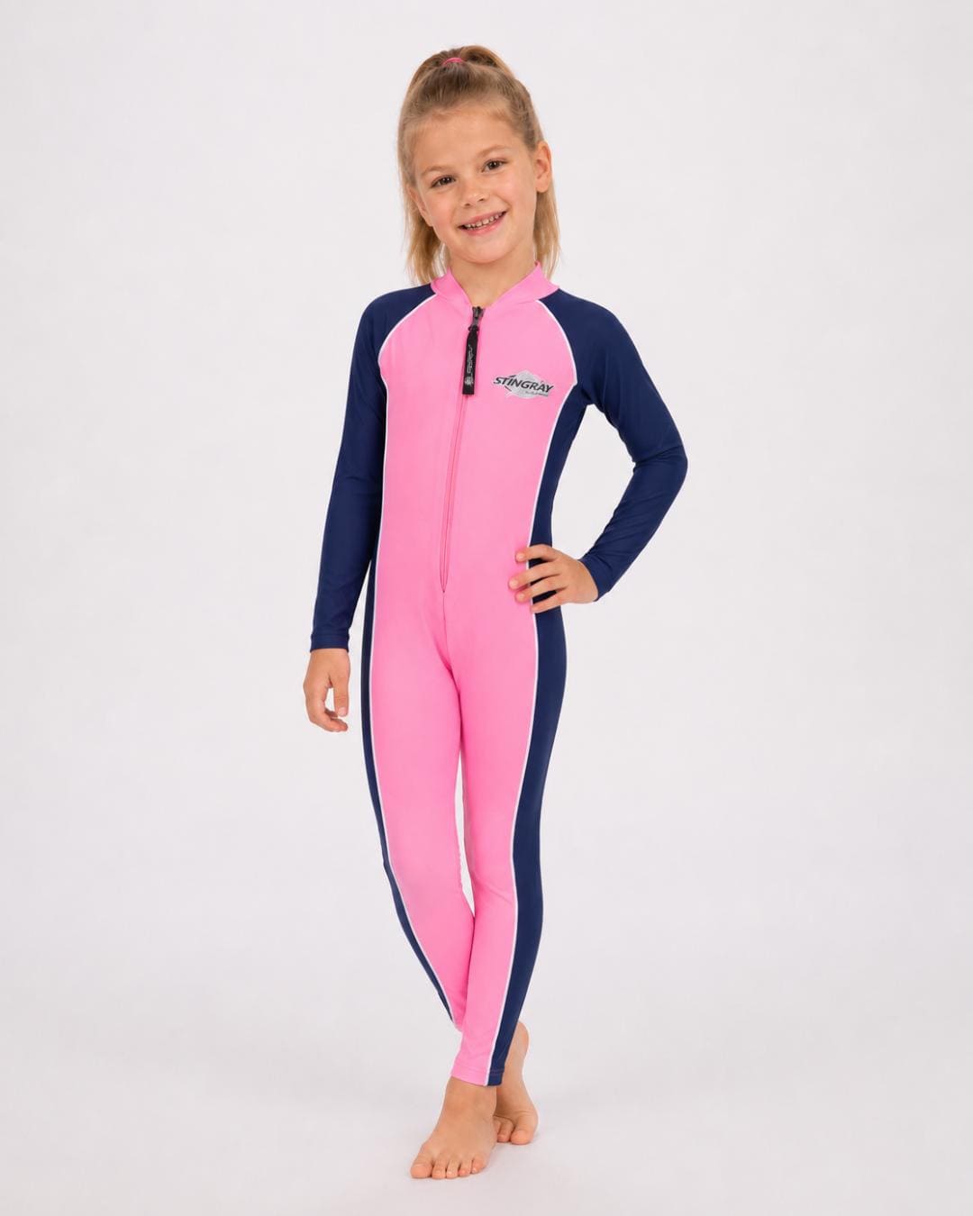 6 year old girl wearing a pink and navy full-body UV swimsuit on a white background