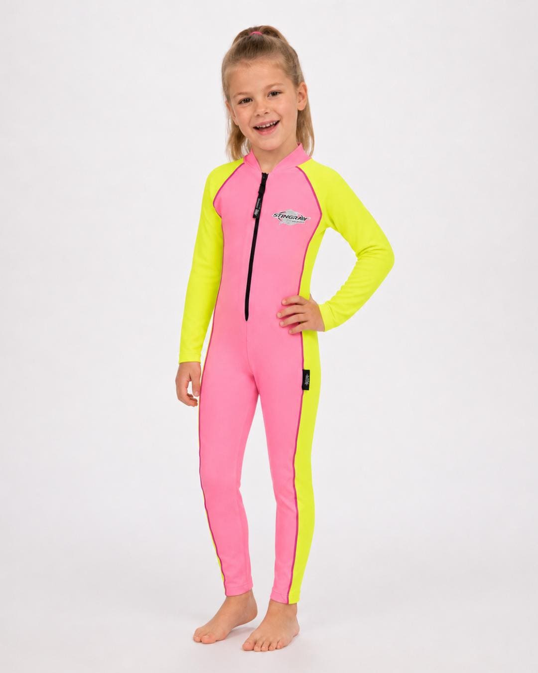 6 year old girl wearing a pink and yellow full-body UV swimsuit on a white background