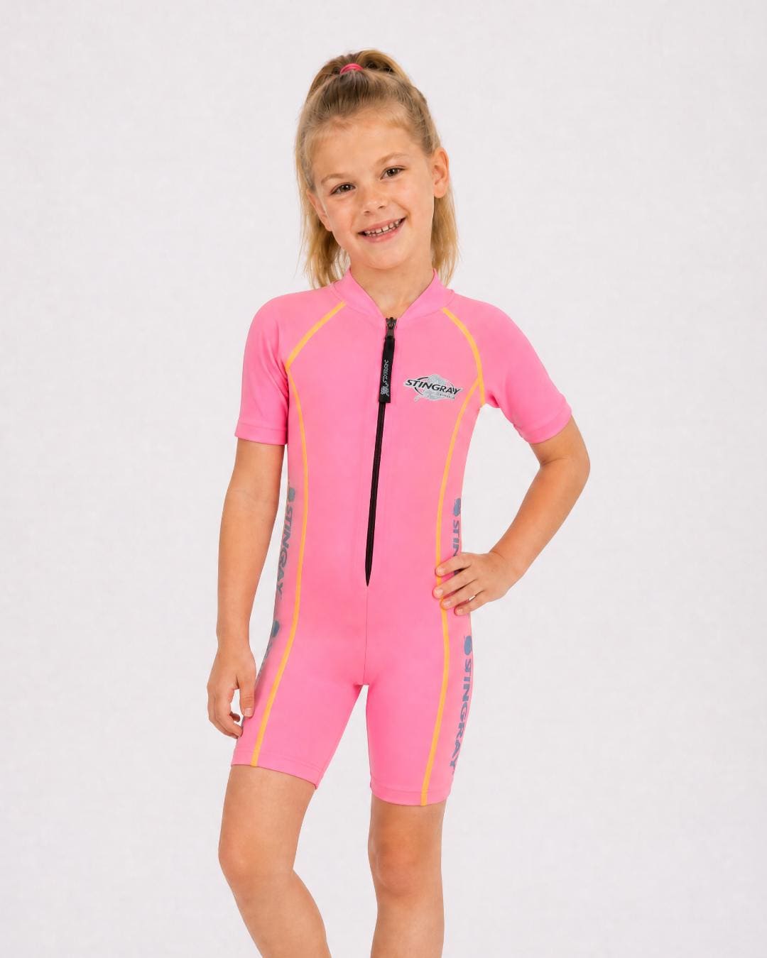 6 year old girl wearing a pink sun protection swimsuit with short sleeves on a white background