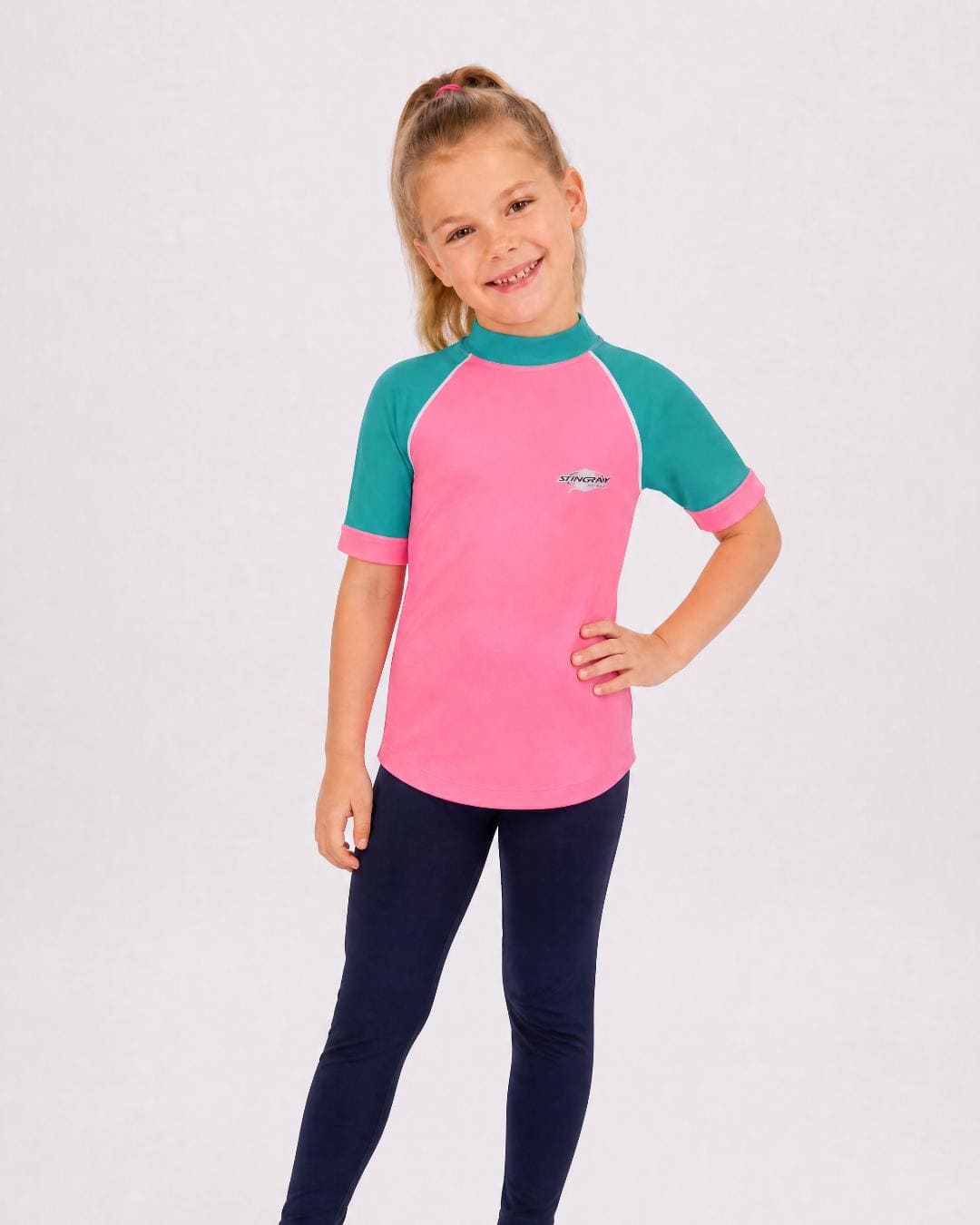 6 year old girl wearing UV rash vest UPF 50+ in pink and teal in a white studio