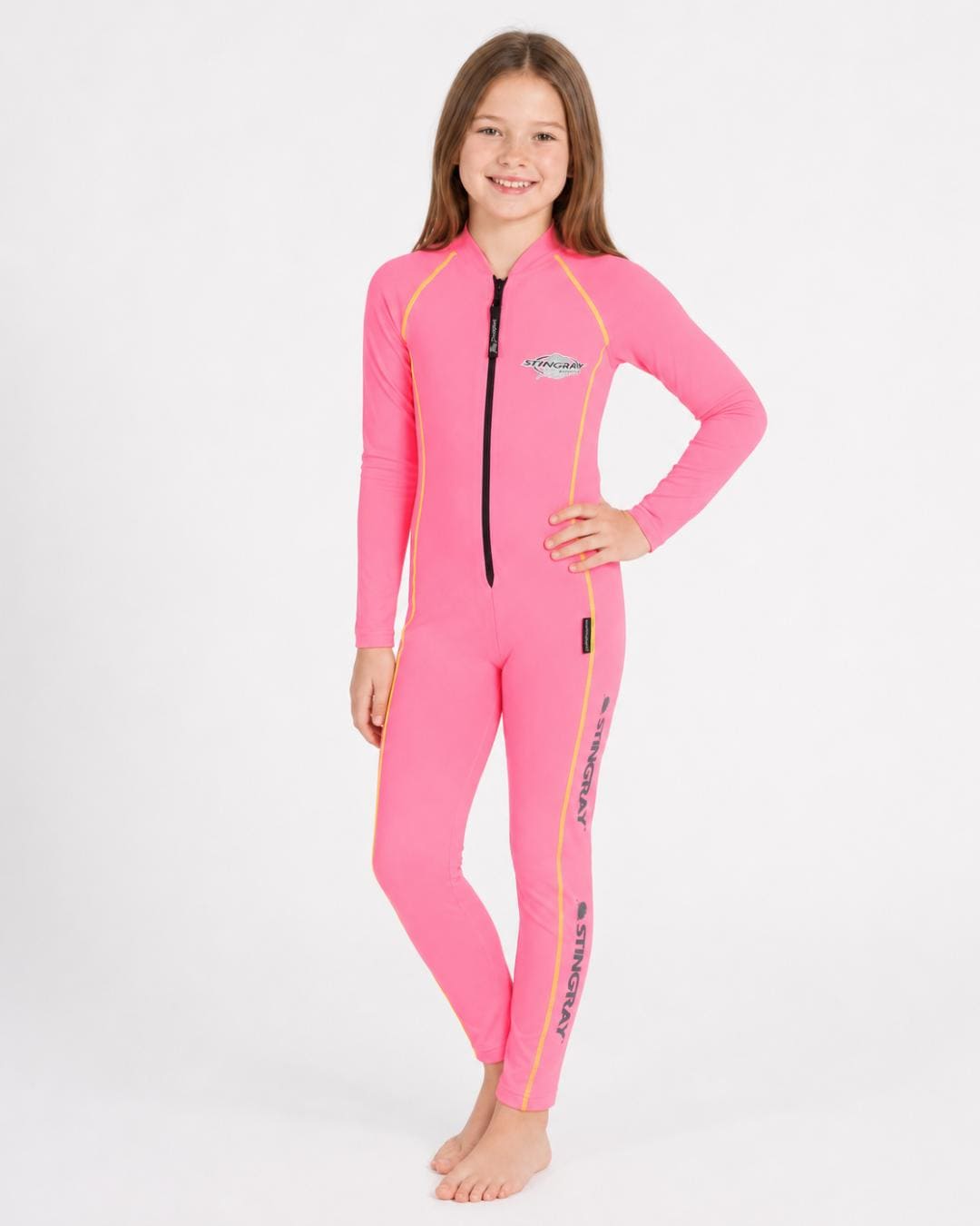 8 year old girl wearing a pink, with orange stitching, full-body UV swimsuit on a white background