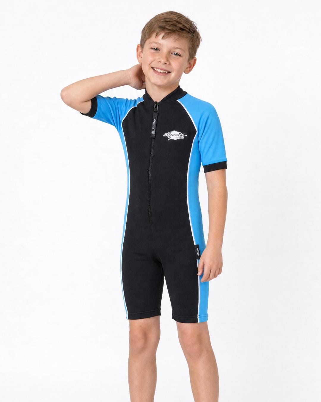 8 year old boy wearing a black and blue UPF short sleeve swimsuit on a white background