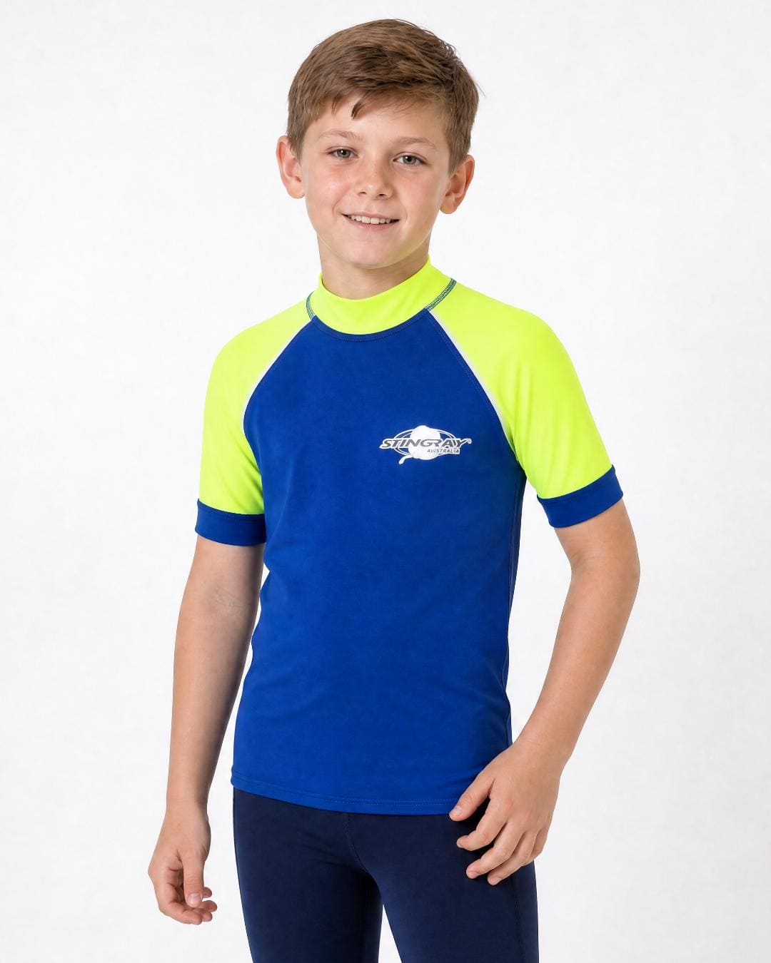 8 year old boy wearing UV rash vest UPF 50+ in ocean blue and yellow in a white studio