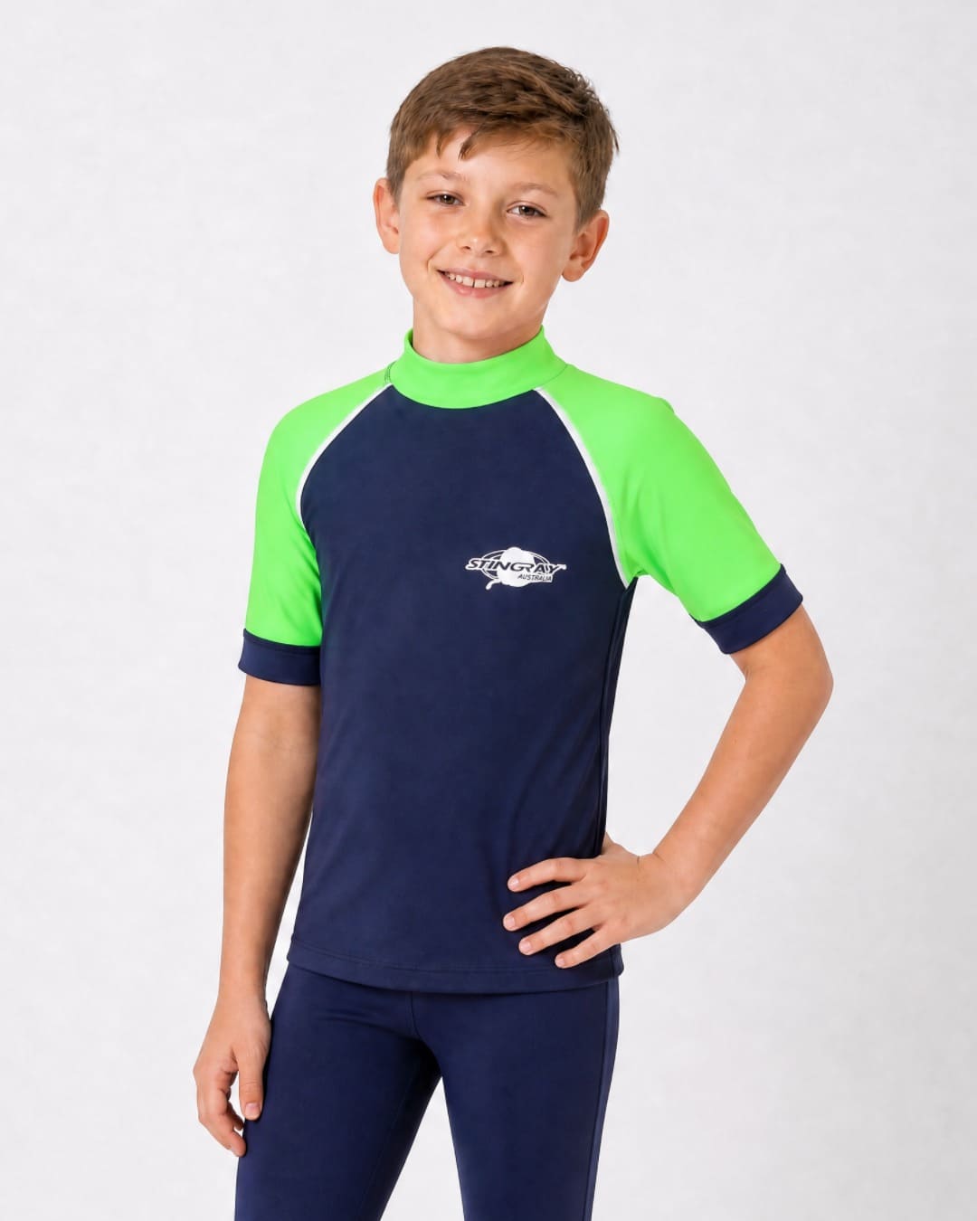 8 year old boy wearing UV rash vest UPF 50+ in navy and green in a white studio