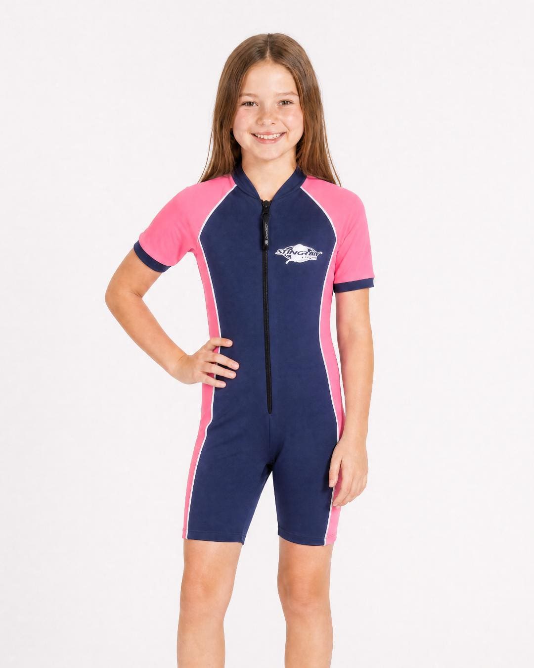 8 year old girl wearing a pink and navy sun protective short sleeve swimsuit on a white background