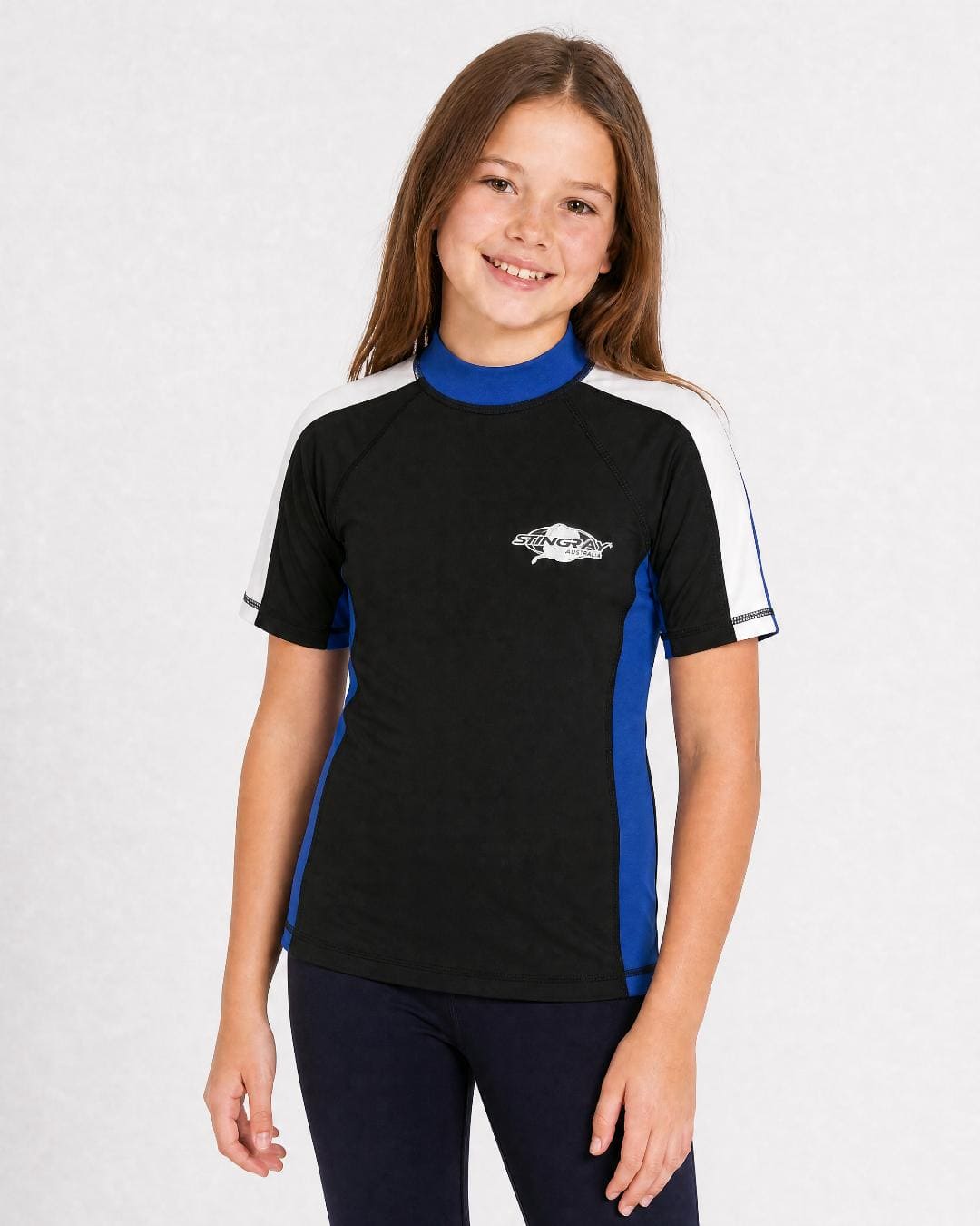 8 year old girl wearing UV rash vest UPF 50+ in black, ocean blue and white in a white studio