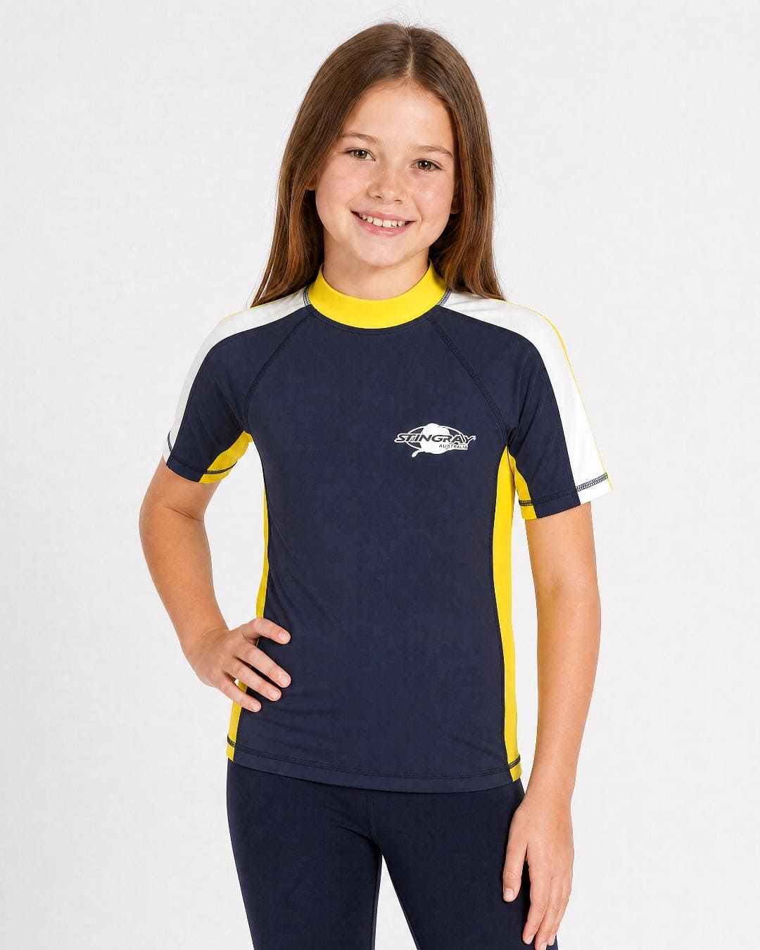 8 year old girl wearing UV rash vest UPF 50+ in navy, yellow and white in a white studio
