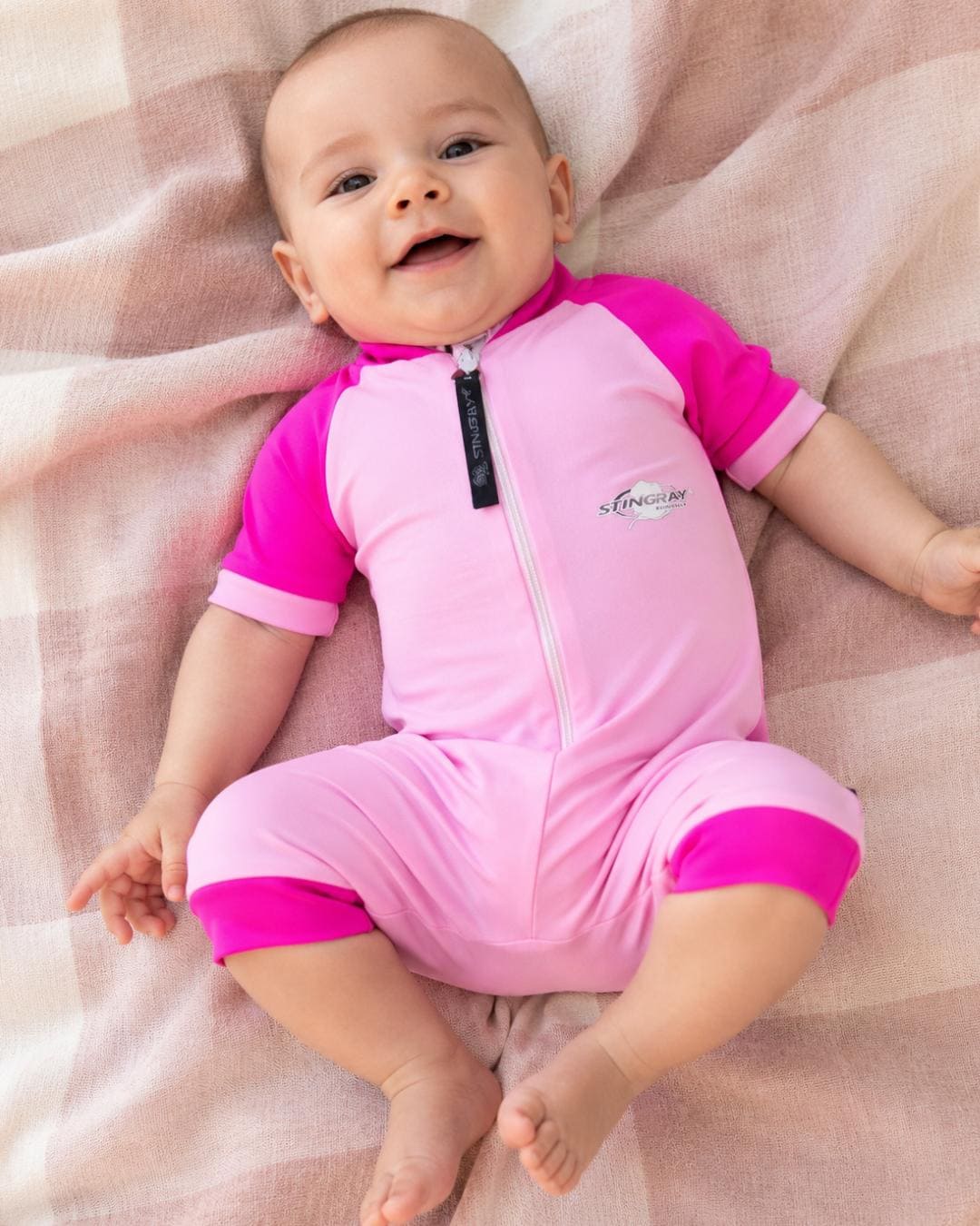 Baby wearing UV full body romper suit UPF 50+ lying on a blanket