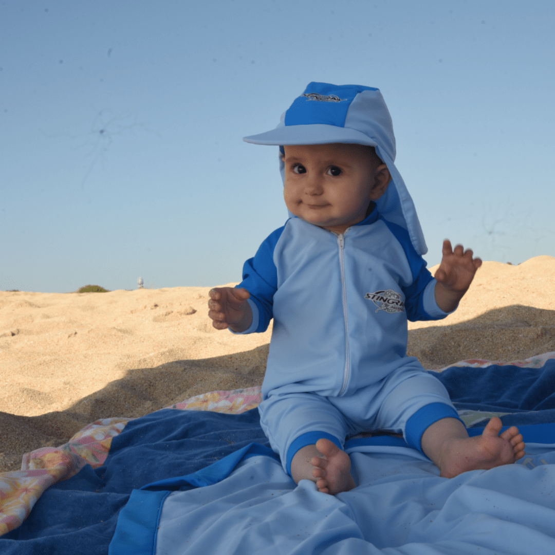 Baby wearing upf sunsuit in blue on the beach
