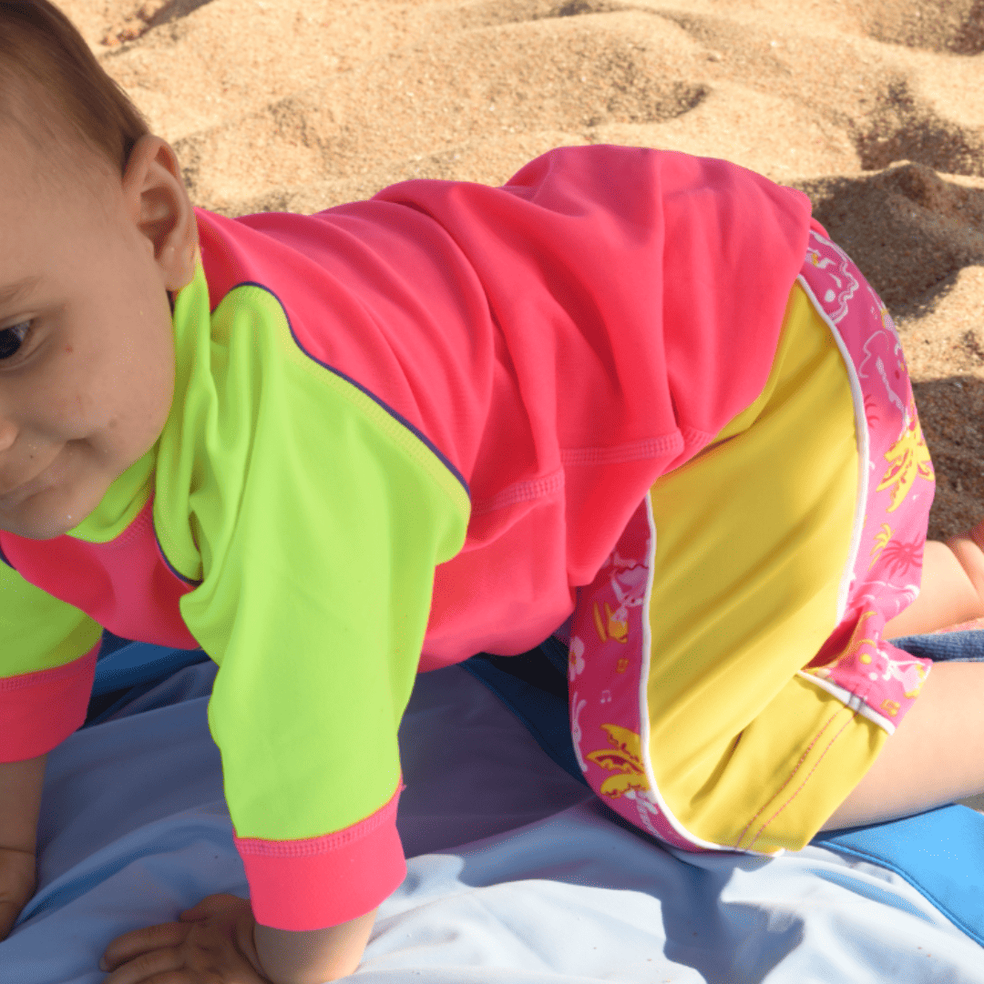Newborn wearing UPF50 swim shorts and rash shirt