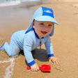 Baby wearing UPF legionnaire cap on the beach