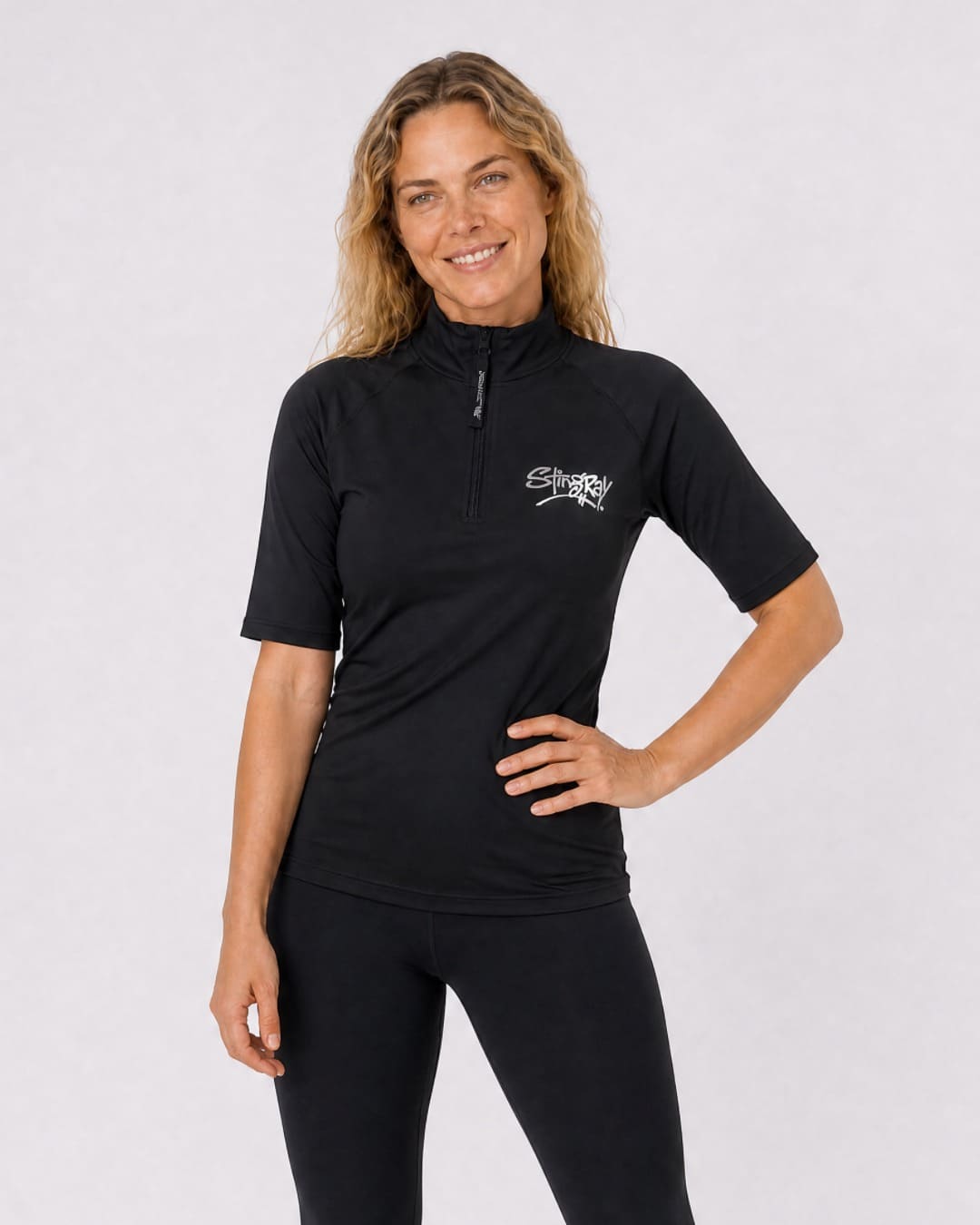 Woman wearing a black short-sleeve zipped UV swim top on a white background