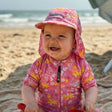 Child in a pink floral outfit and UPF 50+ legionnaire hat on a beach