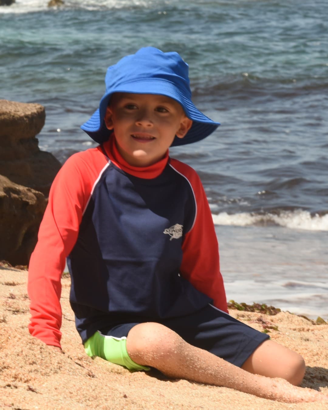Child wearing the ocean blue UV bucket hat UPF 50+ on beach