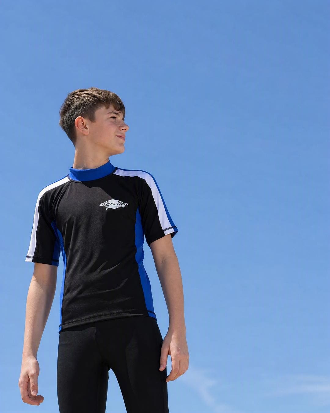 Lifestyle of 13 year old boy wearing short sleeve uv rash vest UPF 50+ - black blue white
