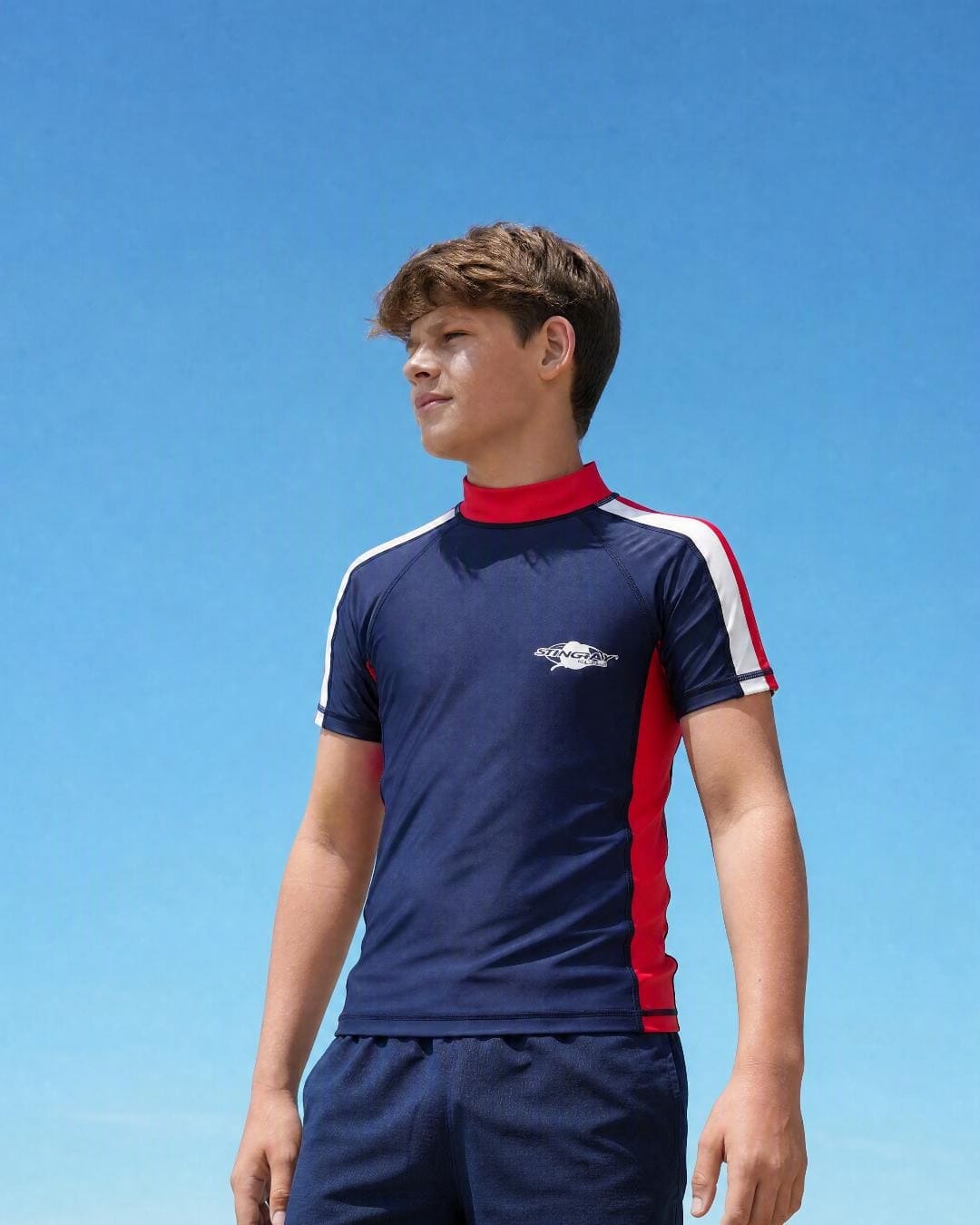 Lifestyle of 13 year old boy wearing short sleeve uv rash vest UPF 50+ - navy red white
