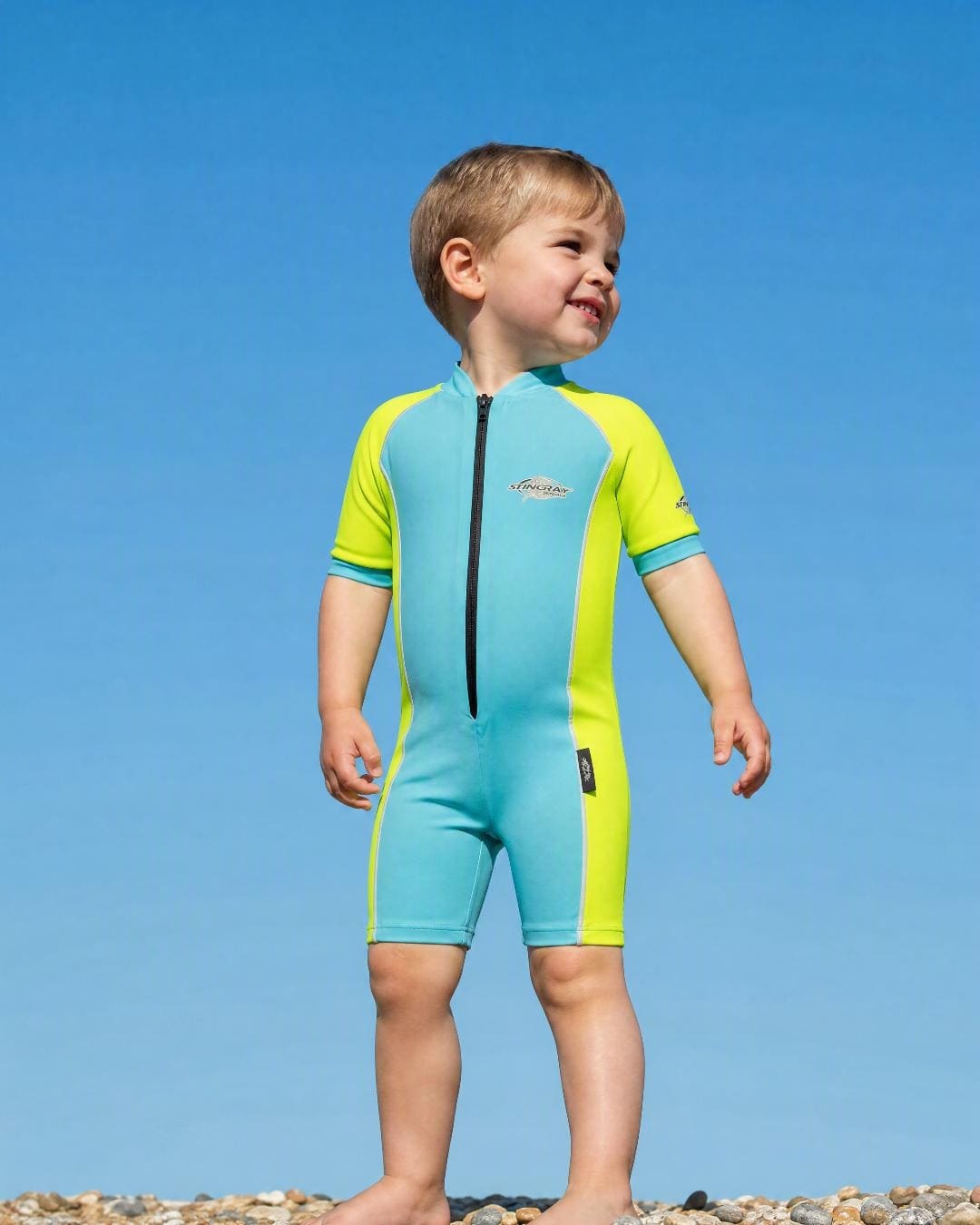 Lifestyle of 2 year old toddler wearing short sleeve UV sunsuit - aqua yellow