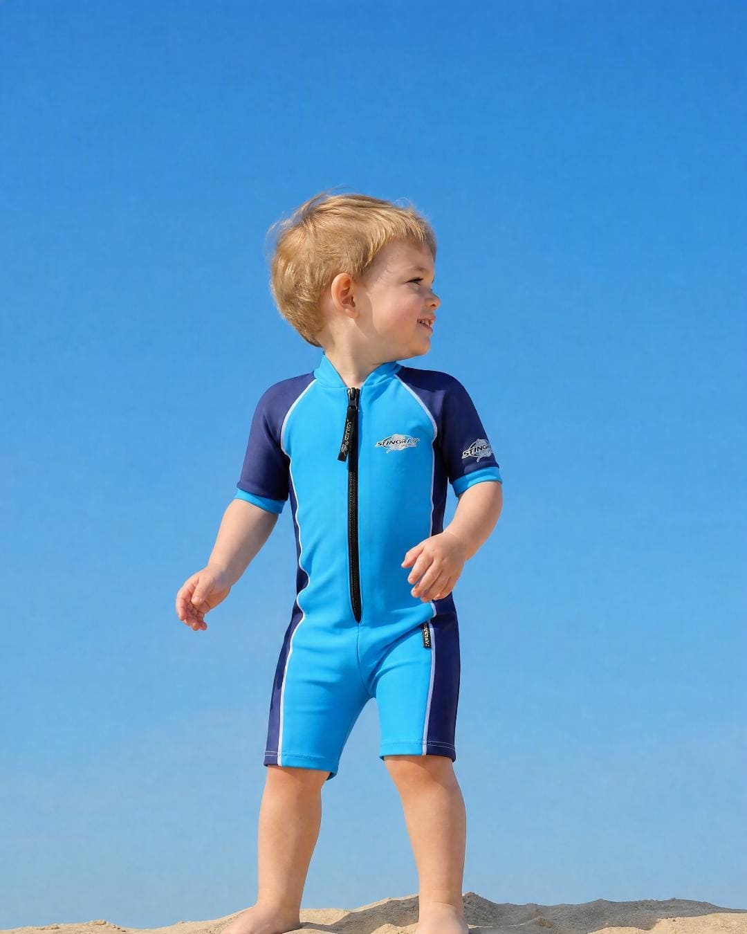 Lifestyle of 2 year old toddler wearing short sleeve UV sunsuit - azure navy