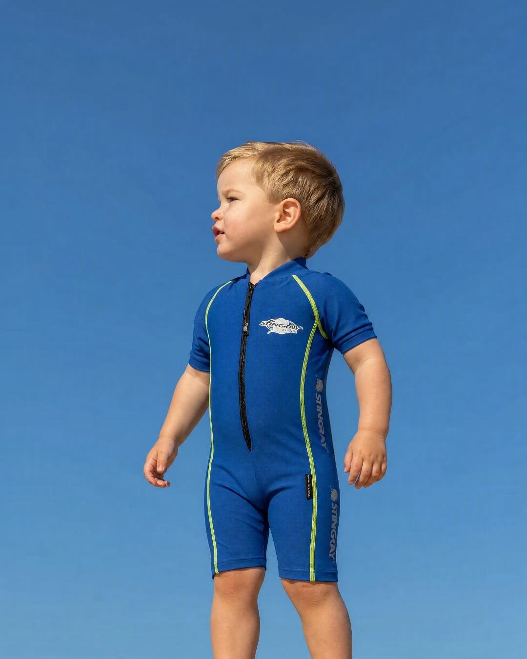 Lifestyle of 2 year old toddler wearing short sleeve UV sunsuit - blue