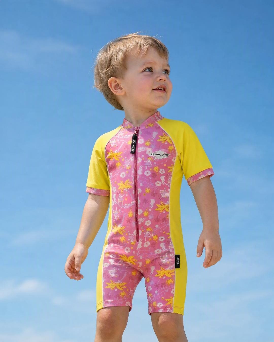 Lifestyle of 2 year old toddler wearing short sleeve UV sunsuit - floral yellow
