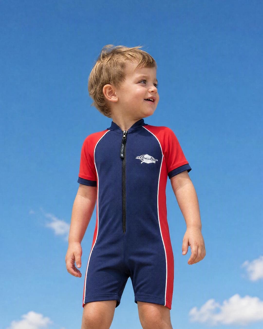 Lifestyle of 2 year old toddler wearing short sleeve UV sunsuit - navy red