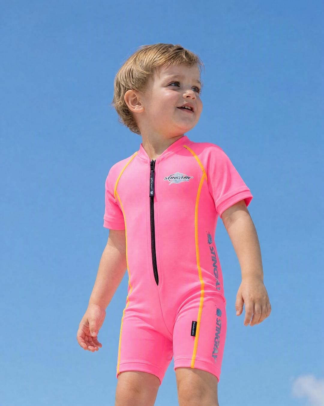 Lifestyle of 2 year old toddler wearing short sleeve UV sunsuit - pink