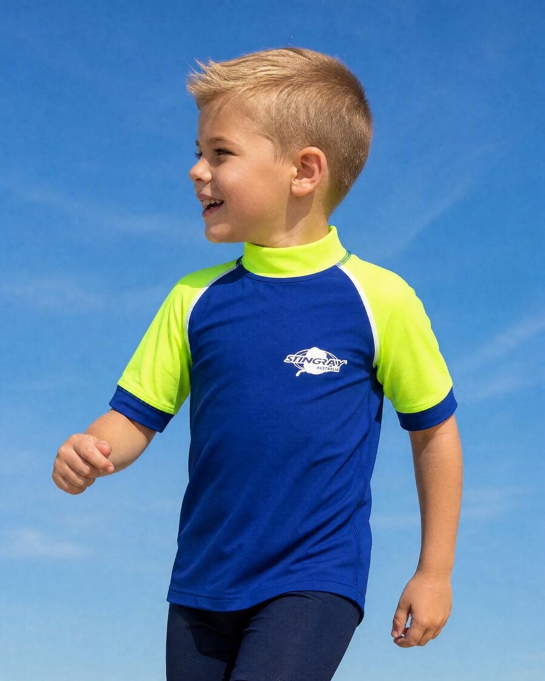Boy at the beach in a kids' short sleeve UV swim shirt UPF 50+ in blue and yellow