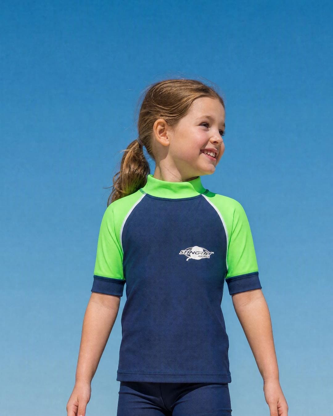 Lifestyle of 6 year old girl wearing short sleeve uv rash vest UPF 50+ - navy green