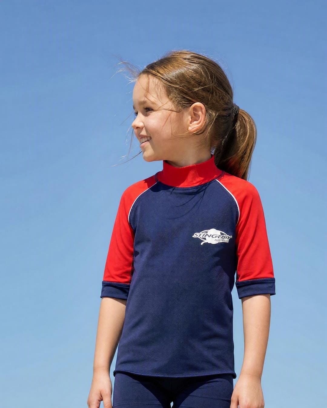 Lifestyle of 6 year old girl wearing short sleeve uv rash vest UPF 50+ - navy red
