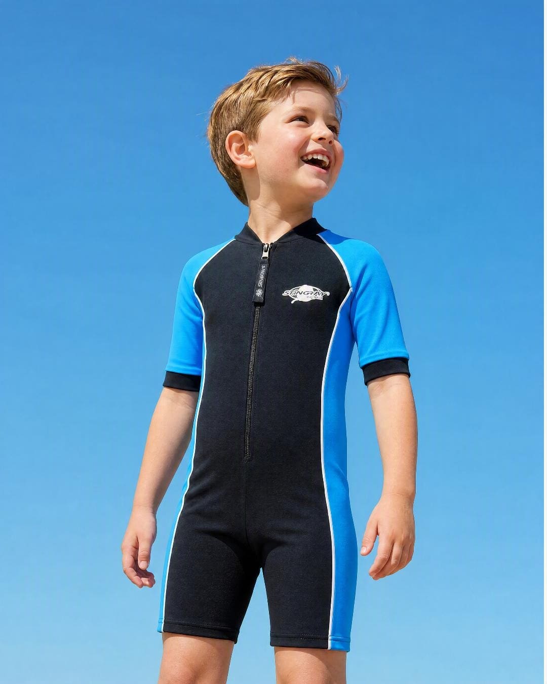 Lifestyle of 8 year old boy wearing short sleeve UV swimsuit UPF 50+ - black blue