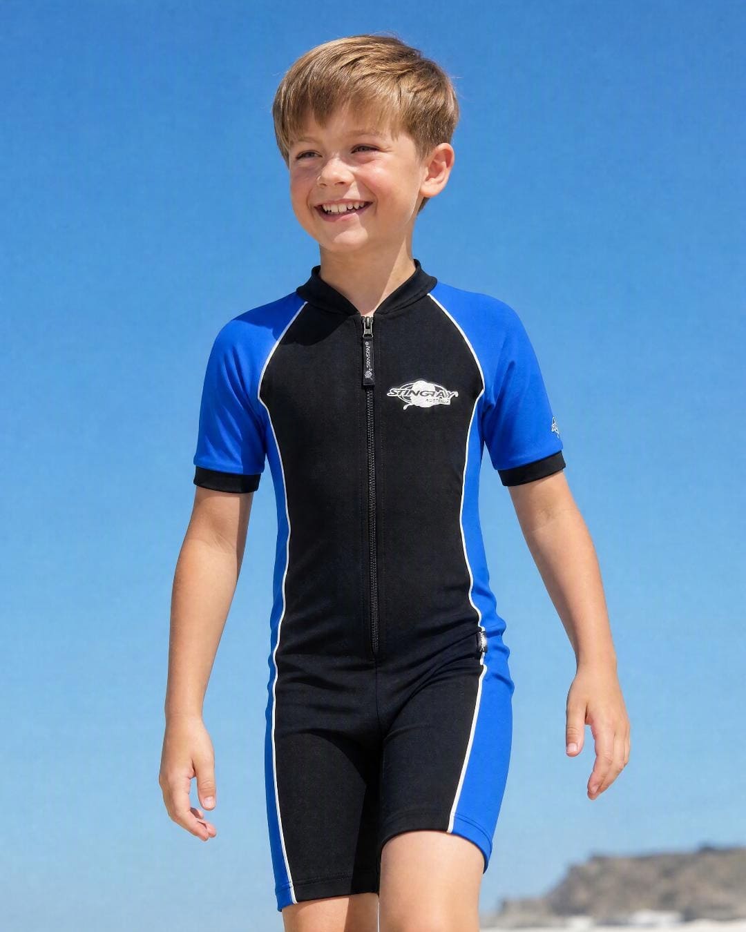 Lifestyle of 8 year old boy wearing short sleeve UV swimsuit UPF 50+ - black dark blue