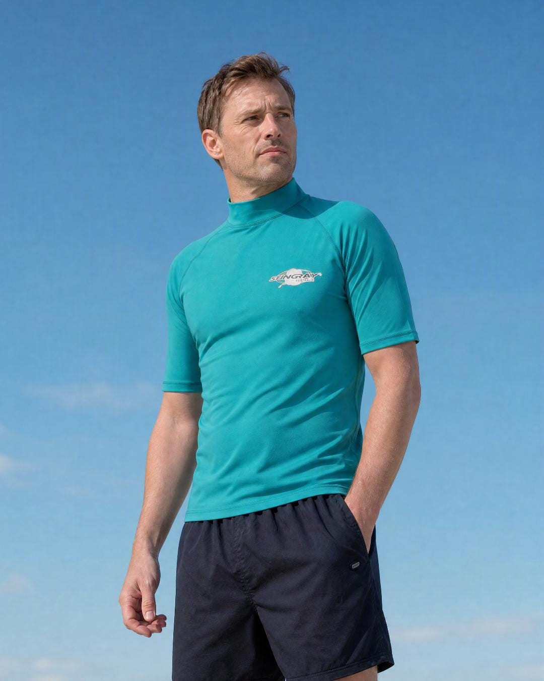 Man wearing a men's short sleeve UV rash vest UPF 50+ in teal at the beach